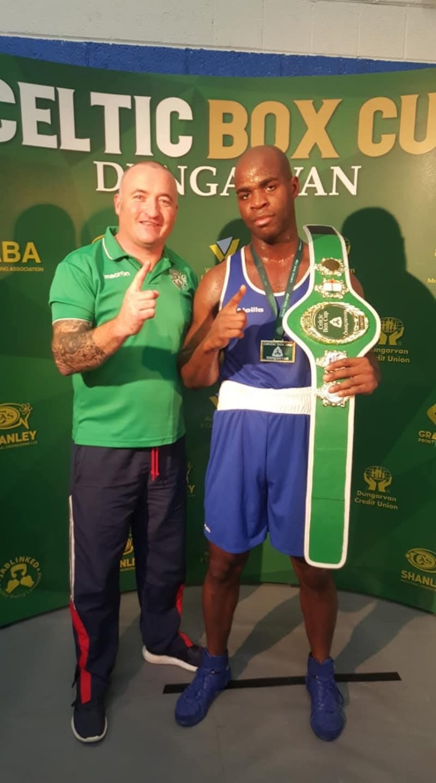 A coach and a boxer holding a green Celtic Box Cup belt in Dungarvan.